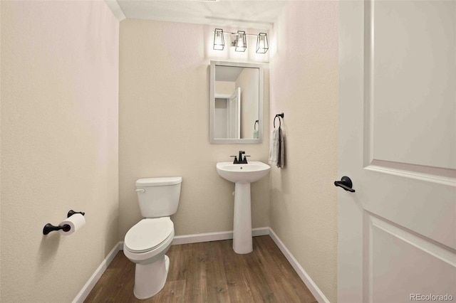 bathroom with a sink, toilet, baseboards, and wood finished floors