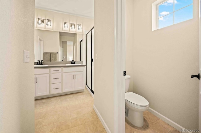 full bath featuring double vanity, toilet, a stall shower, a sink, and baseboards