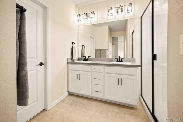 bathroom with a shower stall, baseboards, double vanity, and a sink