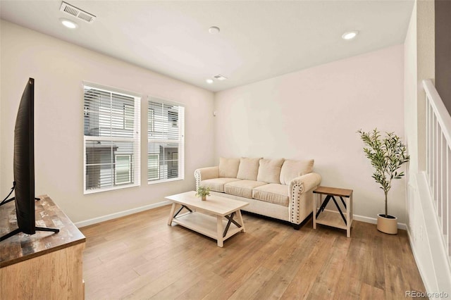 living area featuring baseboards, light wood finished floors, and visible vents