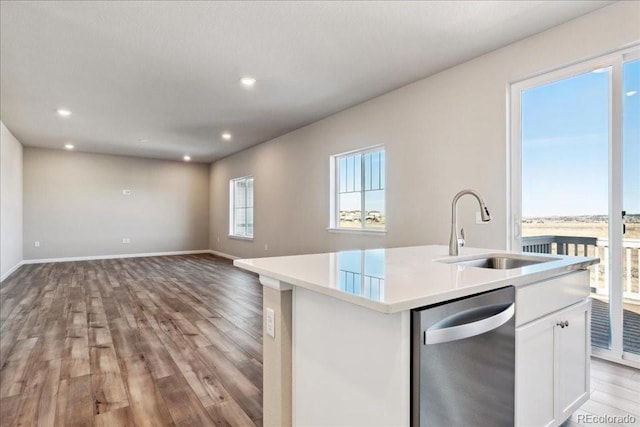 kitchen featuring white cabinets, dishwasher, an island with sink, light hardwood / wood-style floors, and sink