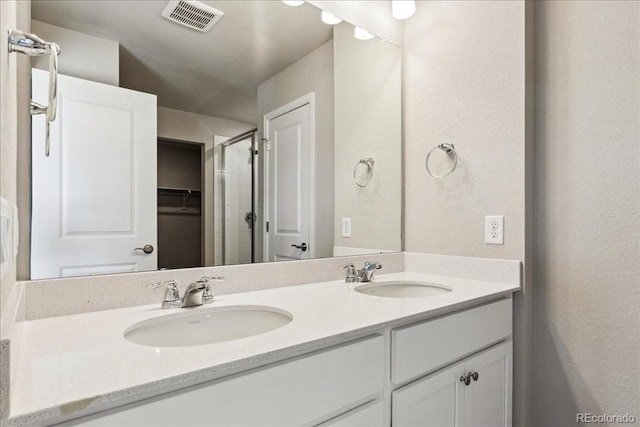 bathroom with a shower with shower door and vanity