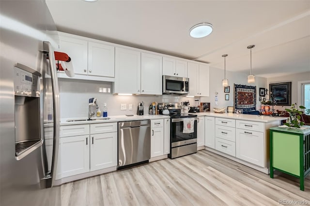 kitchen featuring stainless steel appliances, a peninsula, a sink, white cabinetry, and light countertops