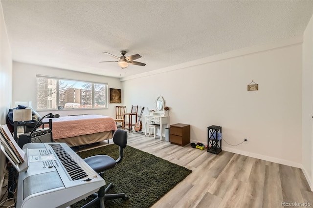 bedroom with ceiling fan, a textured ceiling, baseboards, and wood finished floors