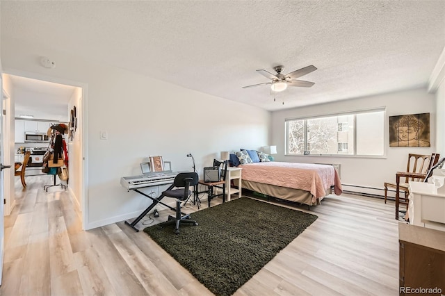 bedroom with a textured ceiling, a ceiling fan, baseboards, baseboard heating, and light wood-type flooring