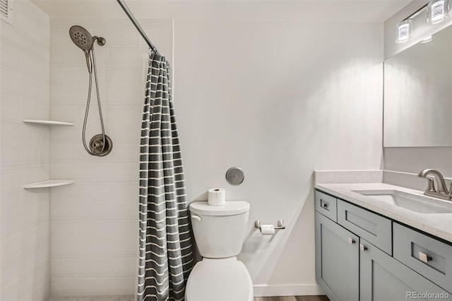 bathroom with tiled shower, vanity, and toilet