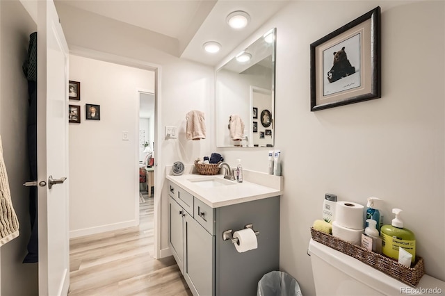 bathroom with toilet, baseboards, wood finished floors, and vanity