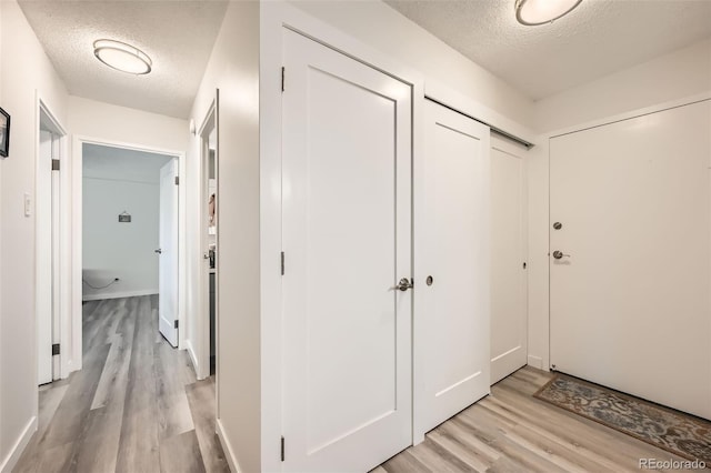 hallway with light wood-style flooring and a textured ceiling