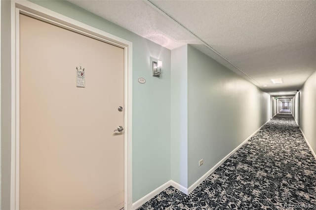 hallway featuring carpet flooring, a textured ceiling, and baseboards