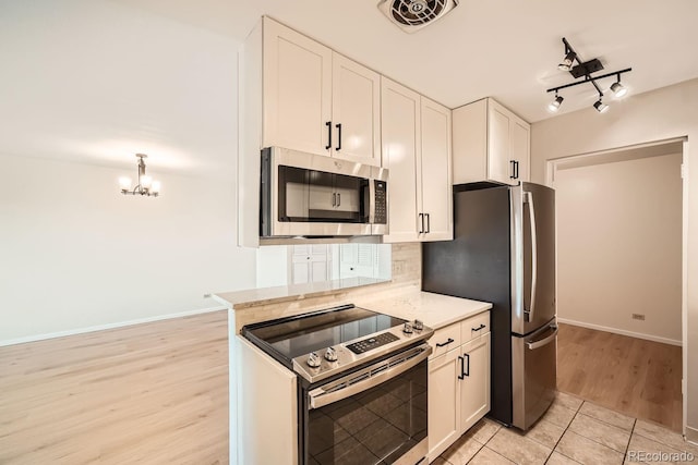 kitchen featuring light stone countertops, white cabinetry, light hardwood / wood-style floors, and appliances with stainless steel finishes