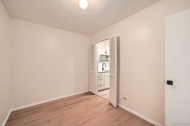 unfurnished bedroom featuring light wood-type flooring, a closet, and sink