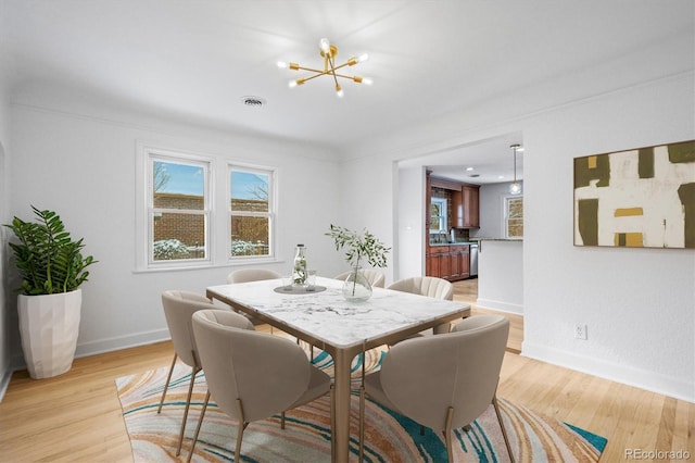 dining space featuring plenty of natural light, a chandelier, and light hardwood / wood-style flooring