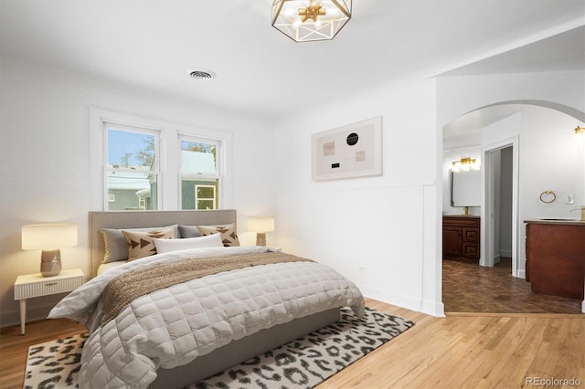 bedroom with hardwood / wood-style flooring and ensuite bath