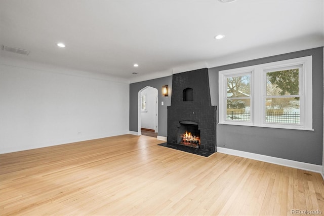 unfurnished living room featuring light hardwood / wood-style flooring and a brick fireplace