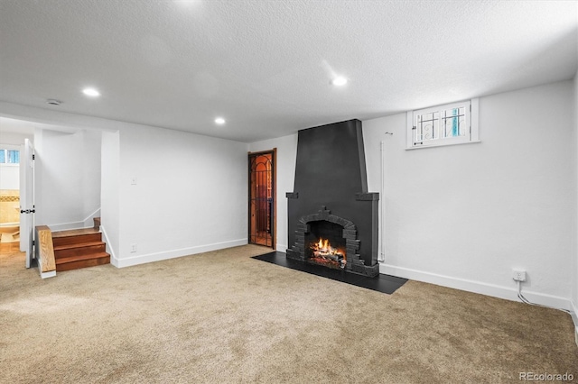 unfurnished living room with carpet flooring, a fireplace, and a textured ceiling