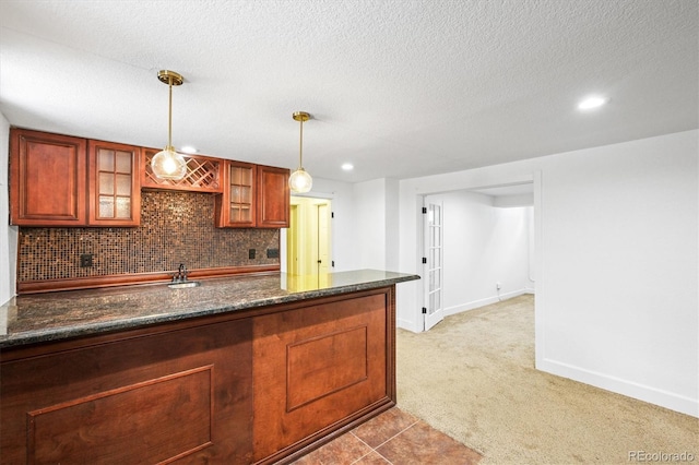 kitchen with light carpet, tasteful backsplash, a textured ceiling, pendant lighting, and dark stone countertops