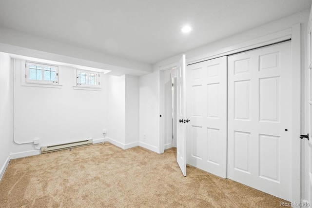 basement featuring light colored carpet and a baseboard heating unit