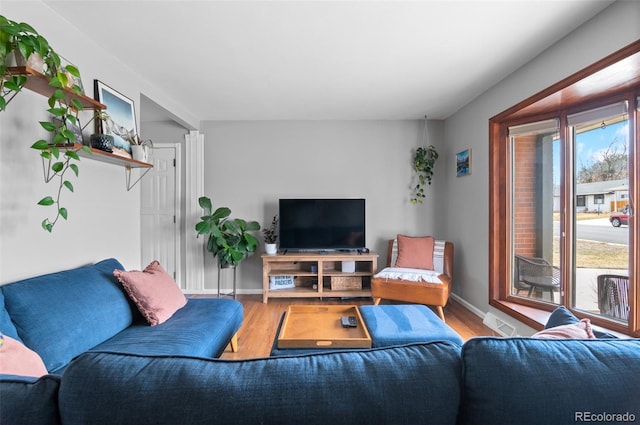 living area with visible vents, baseboards, and wood finished floors