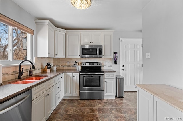 kitchen with tasteful backsplash, white cabinetry, stainless steel appliances, and a sink