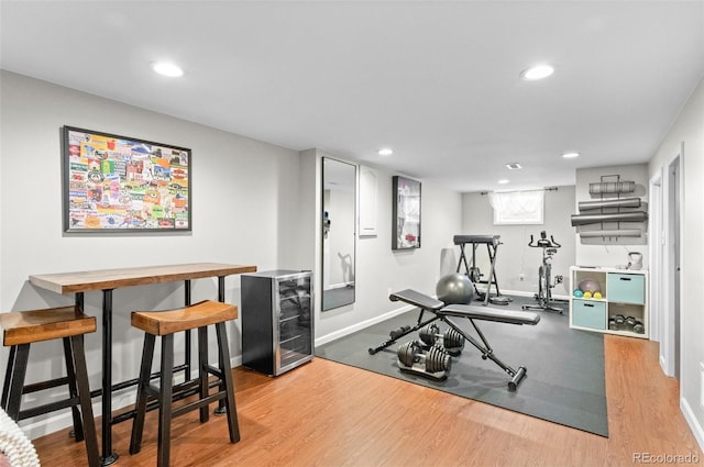 exercise area with beverage cooler, baseboards, wood finished floors, and recessed lighting