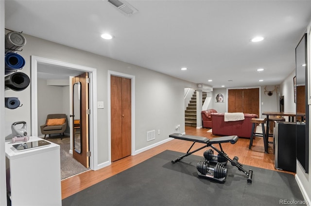 exercise area with recessed lighting, stacked washer / drying machine, visible vents, light wood-style floors, and baseboards