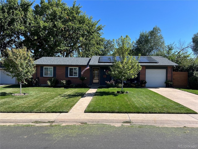 single story home featuring an attached garage, driveway, a front lawn, and brick siding