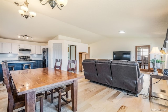 dining room featuring light hardwood / wood-style flooring, vaulted ceiling, and a notable chandelier