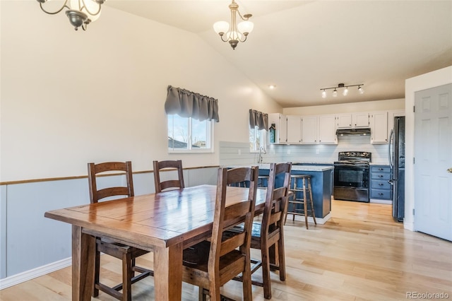 dining area with a chandelier, light hardwood / wood-style flooring, lofted ceiling, and sink