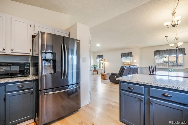 kitchen with white cabinets, light hardwood / wood-style flooring, stainless steel fridge, decorative light fixtures, and a chandelier