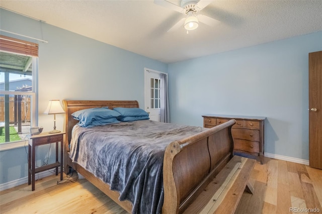 bedroom with multiple windows, a textured ceiling, light hardwood / wood-style flooring, and ceiling fan