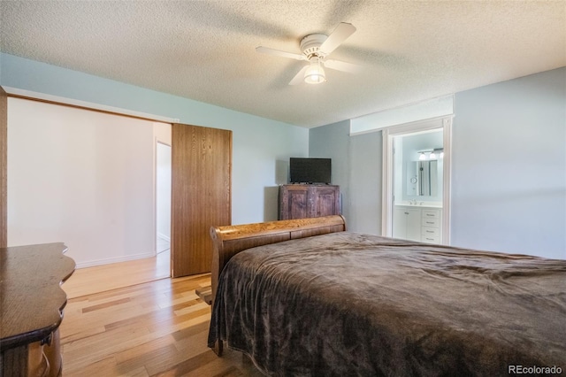 bedroom with connected bathroom, ceiling fan, light hardwood / wood-style flooring, and a textured ceiling