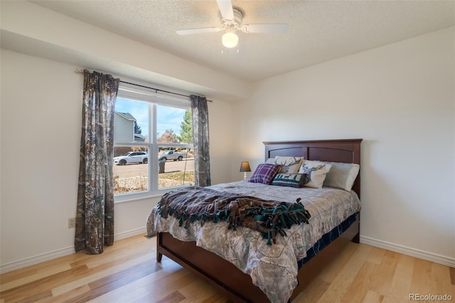 bedroom with a textured ceiling, light hardwood / wood-style flooring, and ceiling fan