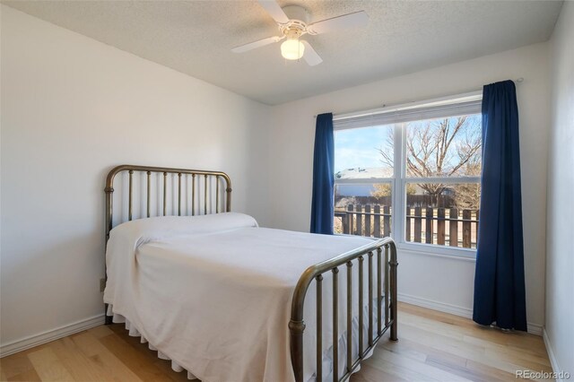 bedroom with ceiling fan, light hardwood / wood-style flooring, and a textured ceiling