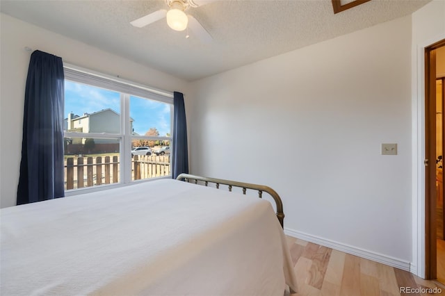 bedroom featuring ceiling fan, a textured ceiling, and light hardwood / wood-style flooring