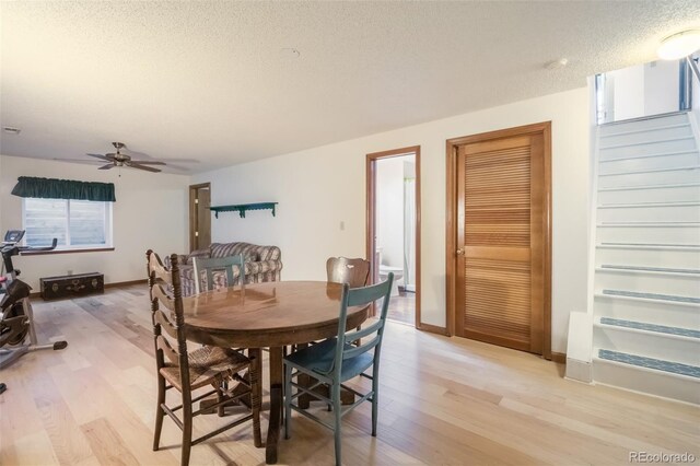 dining area featuring a textured ceiling, light wood-type flooring, and ceiling fan