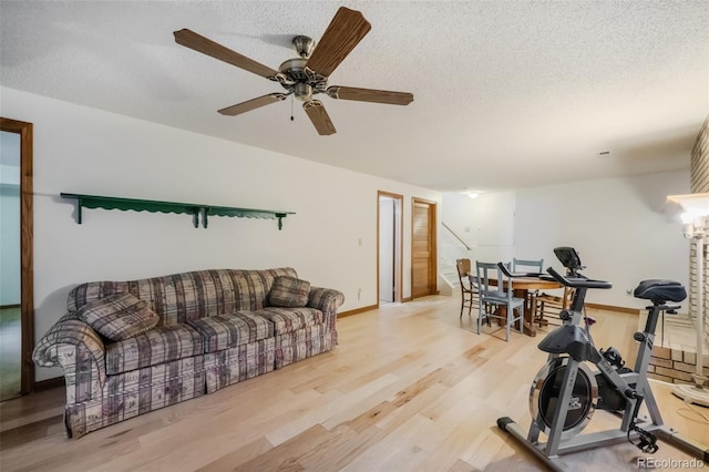 interior space with a textured ceiling, light wood-type flooring, and ceiling fan