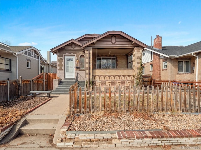 bungalow-style house with a fenced front yard and brick siding