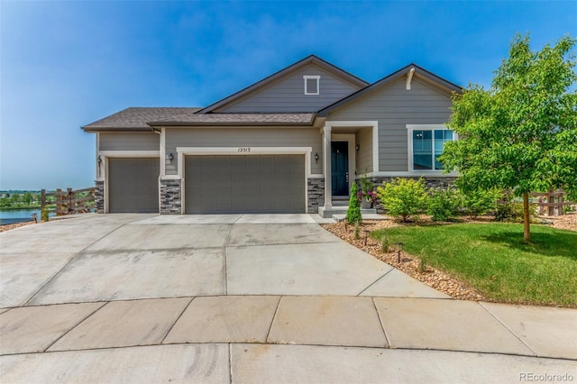 12513 Shore Point St, Firestone, CO 80504 - view of front of house with an attached garage, a front lawn, driveway, and stone siding