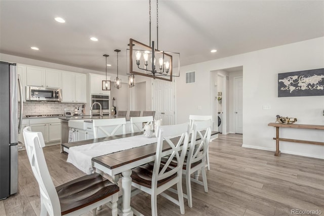 12513 Shore Point St, Firestone, CO 80504 - dining space featuring recessed lighting, light wood-style floors, a chandelier, baseboards, and washer / dryer