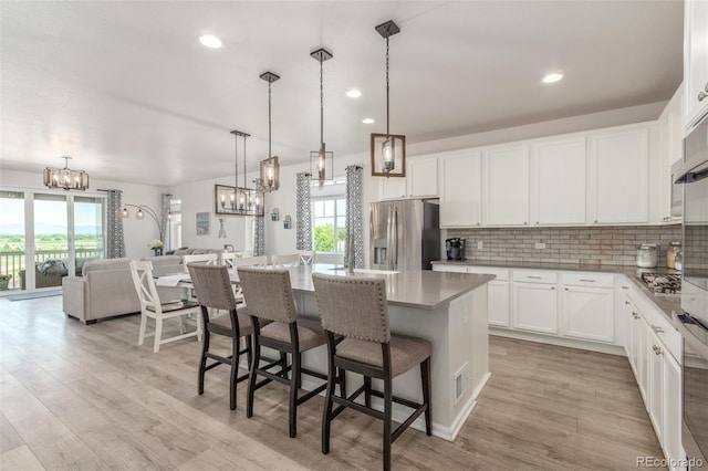 12513 Shore Point St, Firestone, CO 80504 - kitchen featuring stainless steel appliances, a chandelier, backsplash, a kitchen island, and light wood-style flooring