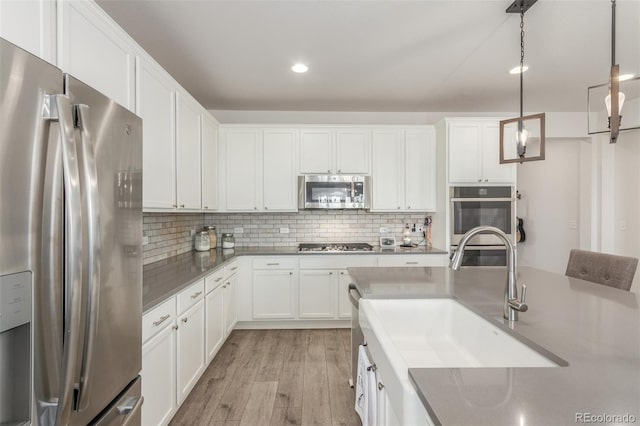 12513 Shore Point St, Firestone, CO 80504 - kitchen with stainless steel appliances, light wood-style flooring, a sink, white cabinetry, and decorative backsplash