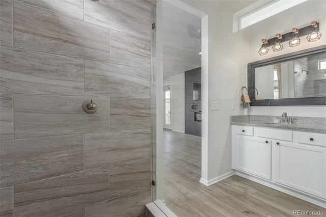 12513 Shore Point St, Firestone, CO 80504 - bathroom featuring a tile shower, vanity, wood finished floors, and baseboards
