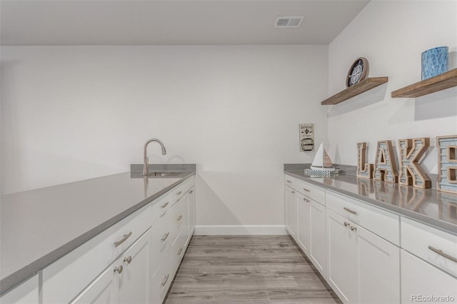 12513 Shore Point St, Firestone, CO 80504 - kitchen with a sink, open shelves, white cabinetry, light wood-style flooring, and baseboards