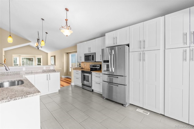 kitchen featuring appliances with stainless steel finishes, white cabinets, decorative light fixtures, and sink