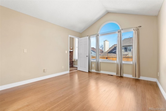 empty room with light wood-type flooring and vaulted ceiling