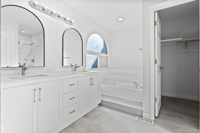 bathroom with a bathtub, wood-type flooring, and vanity