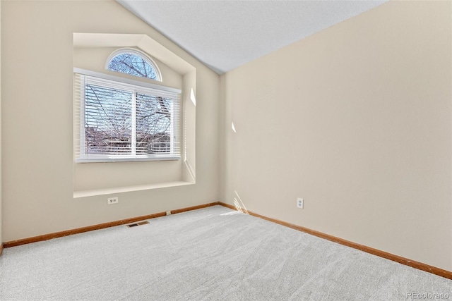 spare room featuring lofted ceiling and carpet flooring