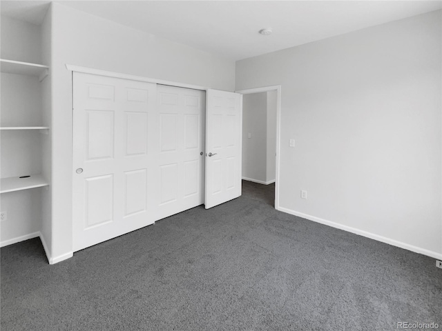 unfurnished bedroom featuring dark carpet and a closet