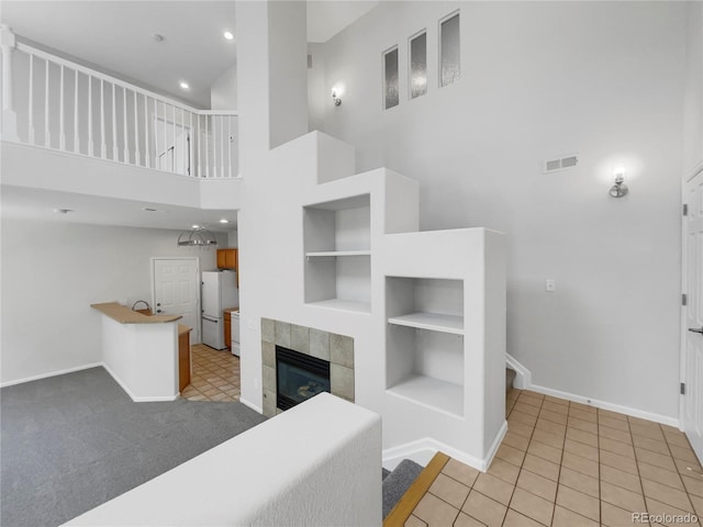 tiled living room with built in shelves, a towering ceiling, and a fireplace