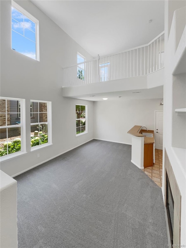 unfurnished living room featuring a high ceiling, sink, and light carpet